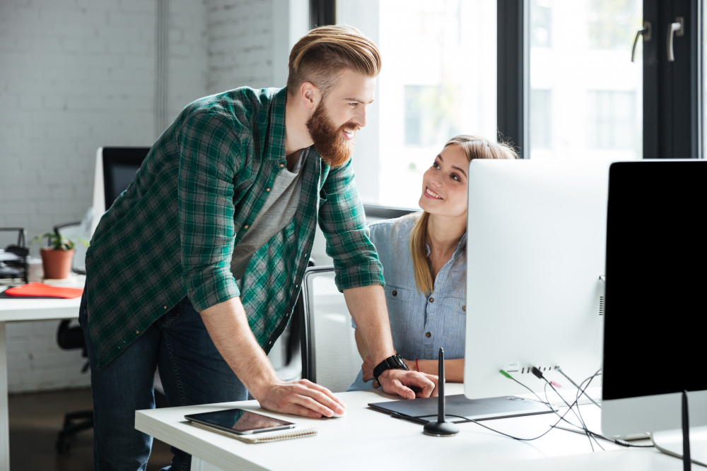 A man and woman focus on a computer, representing teamwork at a premier web design company in Dallas.