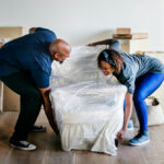 A man and woman collaborating to relocate boxes in a living room, representing the quality of trusted moving services.